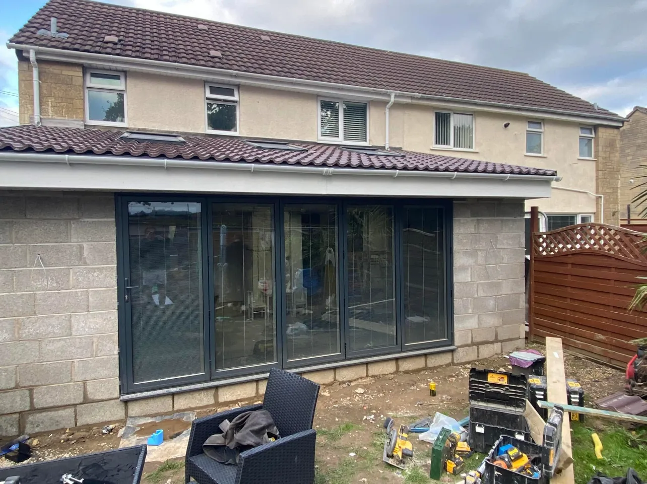 A new single-storey rear extension in blockwork with a tiled lean-to roof and a full-width set of grey bi-fold doors