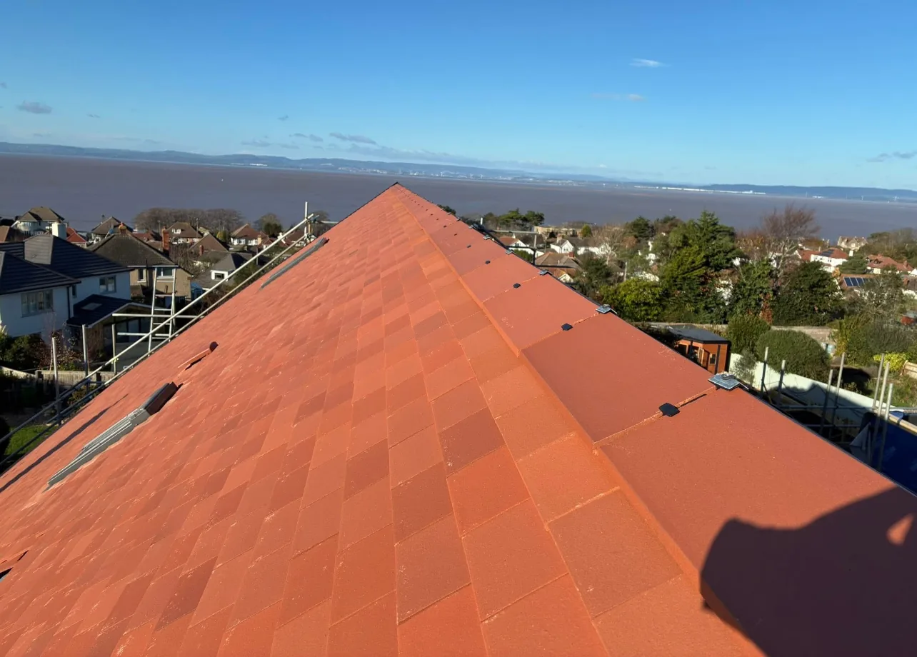 A finished plain clay-tiled roof slope with rooflights, seen along the ridge towards open water