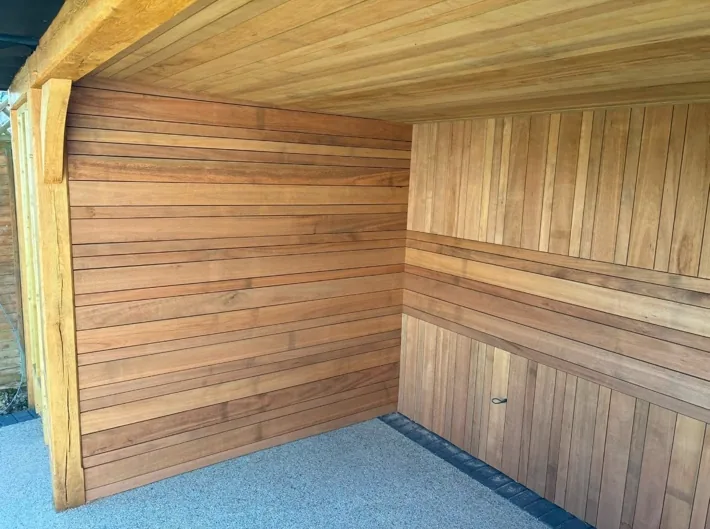Inside a bespoke timber structure: hardwood cladding on the walls, a boarded timber ceiling and an oak post with a curved brace